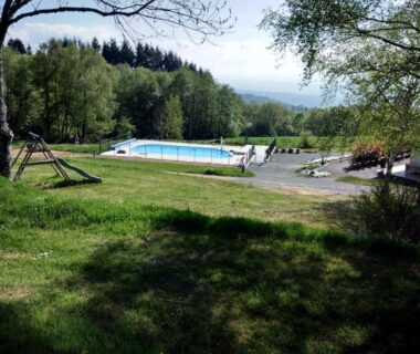 Pelouse en pente et piscine extérieure au Camping le Montbartoux