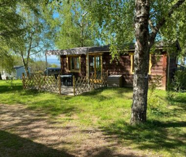 Terrasse en bois sous arbres au Camping le Montbartoux
