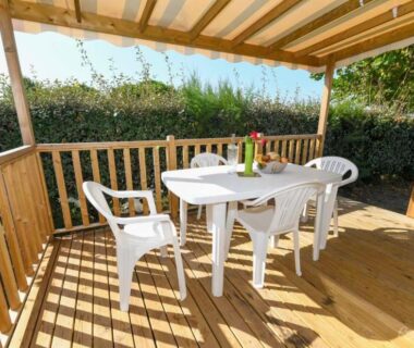 Terrasse couverte avec table et chaises blanches au Camping le Moulin de la Salle
