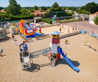 Aire de jeux sur sable avec toboggan et château gonflable au Camping le Moulin de la Salle