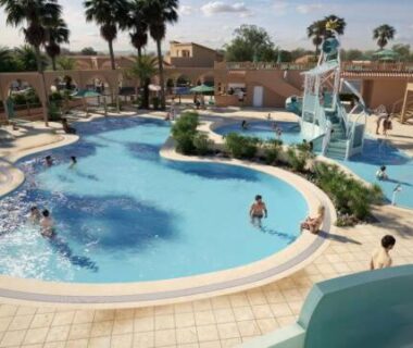 Piscine extérieure avec toboggan et palmiers au Camping le Neptune