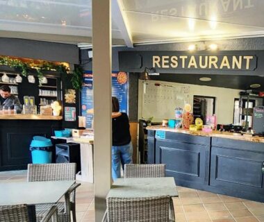 Salle de restaurant avec comptoir et tables au Camping le Neptune