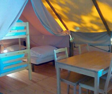 Intérieur de tente avec lits table et chaises au camping le Nid du Parc