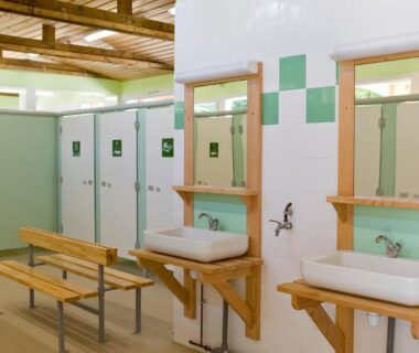 Vestiaire avec lavabos, miroirs, bancs et cabines au Camping le Nid du Parc