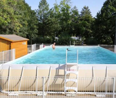 Piscine hors sol entourée d'arbres au Camping le Nid du Parc