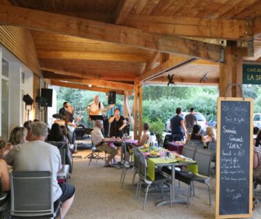 Terrasse couverte avec musiciens et convives au Camping le Nid du Parc
