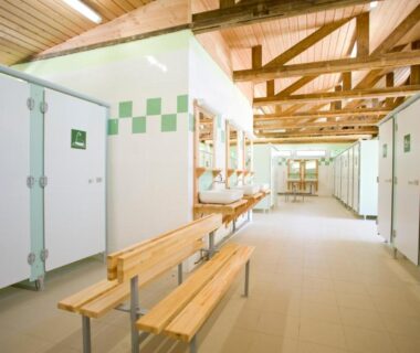 Bloc sanitaire avec douches lavabos et bancs du Camping le Nid du Parc