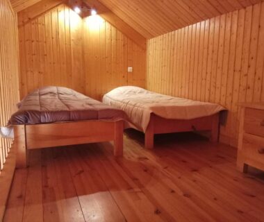 Mezzanine avec deux lits en bois et murs lambrissés au Camping le Pré Morjal