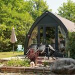 Terrasse et salon de jardin devant un pod de glamping au Camping le Pré Morjal