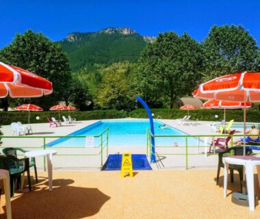 Piscine extérieure entourée de parasols et tables au Camping le Pré Morjal