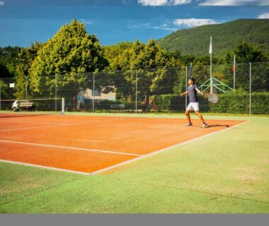 Terrain de tennis extérieur avec joueur au Camping le Pré Morjal