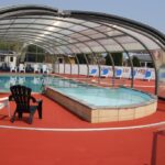 Piscine couverte sous dôme avec chaises longues au Camping le Rivage