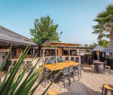 Terrasse en bois avec tables et chaises au Camping le Roucan West