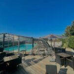 Terrasse en bois avec tables et piscine sous abri du Camping le Rouge Gorge