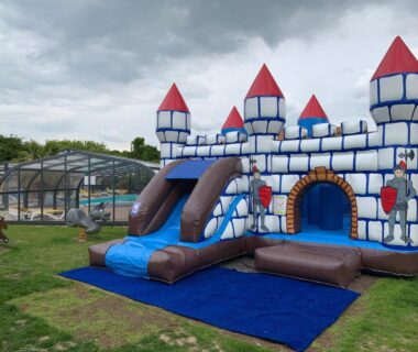 Aire de jeux gonflable sur la pelouse et piscine couverte au Camping le Rouge Gorge
