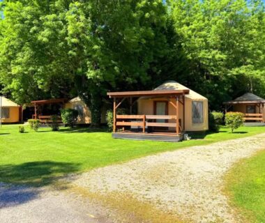 Allées gravillonnées et lodges en bois dans parc arboré au Camping le beauvillage Lauzerte