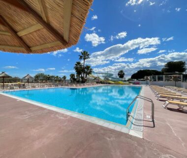 Bord de piscine avec parasols et transats au Camping le lac des rêves L’ABRIZEN 254