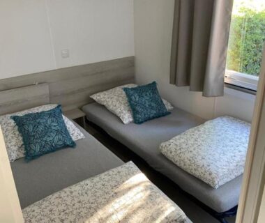 Chambre avec deux lits simples et rideaux dans le mobil home Séléna