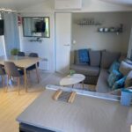 Intérieur avec salon canapé et coin repas du mobil home Séléna