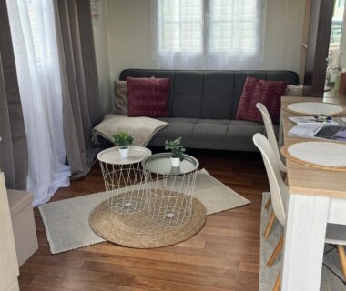 Salon intérieur avec canapé, tables basses et coin repas au Camping le petit RIO