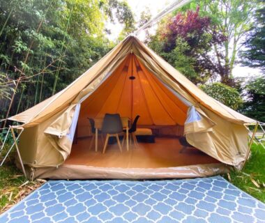 Sur le gazon tente lodge ouverte avec tapis et mobilier intérieur au Camping les Avenières