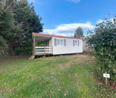 Emplacement herbeux avec mobil-home et terrasse sous arbres au Camping les Avenières