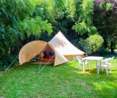Emplacement herbeux avec tente et salon de jardin au Camping les Avenières