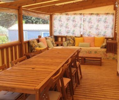 Terrasse en bois couverte avec table et banquette du Camping les Cigales Tikayan