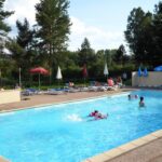 Piscine extérieure avec baigneurs et transats au Camping les Pinasses