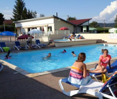 Bord de la piscine avec baigneurs et transats au Camping les Pinasses