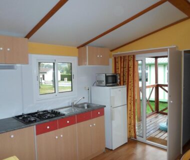 Intérieur kitchenette avec cuisinière et réfrigérateur au camping les Pinasses
