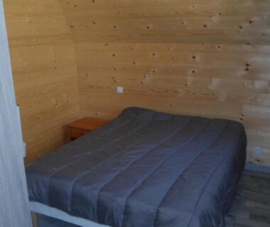 Chambre avec lit double dans chalet en bois au Camping les Pinasses