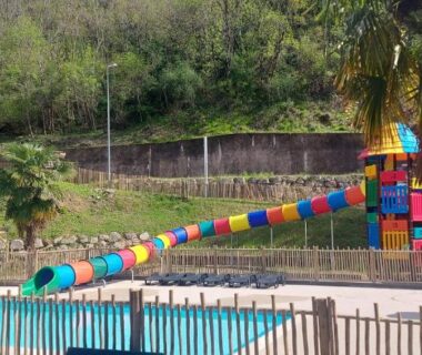 Piscine et aire de jeux avec toboggan coloré au Camping les Sables
