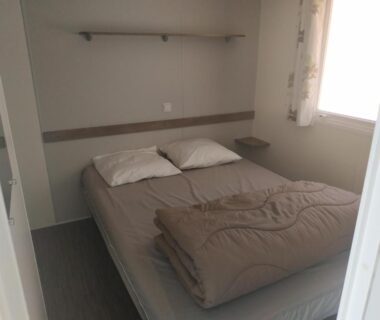 Chambre avec lit double et couette pliée au Camping les Sables