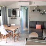 Séjour avec canapé, table et télévision dans le mobil-home du Camping les Sables du Midi