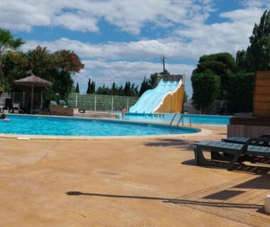 Piscine extérieure avec toboggan et transats au Camping les Salins de la Gardiole
