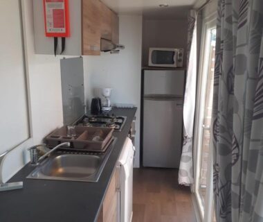 Cuisine équipée avec évier, plaques et réfrigérateur dans le mobil-home au Camping les Salins de la Gardiole