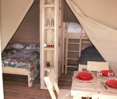 Intérieur de tente avec lits superposés et table dressée au Camping les Silhols