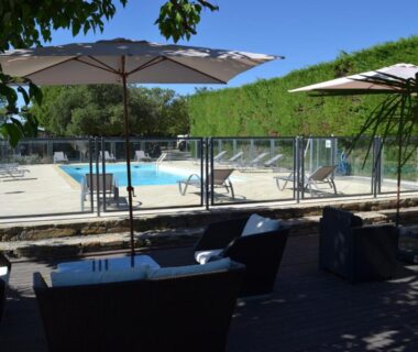 Terrasse ombragée avec salon et piscine au Camping les Silhols