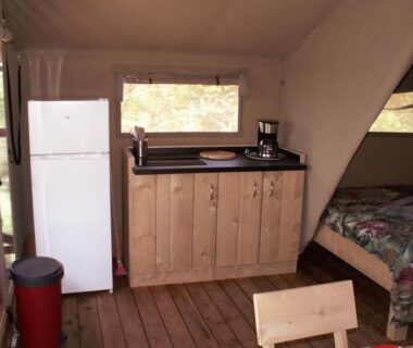 Intérieur de tente avec kitchenette frigidaire et lit au Camping les Silhols