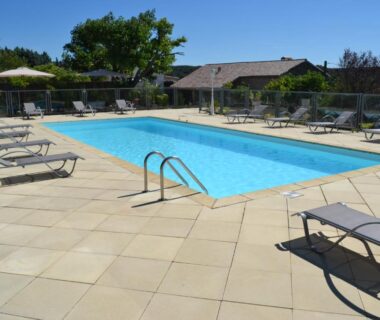 Piscine extérieure entourée de transats et parasols au Camping les Silhols