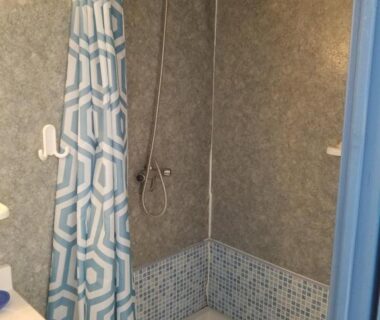 Douche cabine avec rideau géométrique dans le mobilhome au Camping les Tourterelles Chalets et mobilhomes