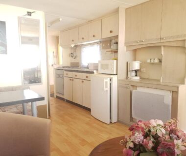 Intérieur avec kitchenette réfrigérateur et coin repas dans le mobilhome du Camping les Tourterelles Chalets et mobilhomes
