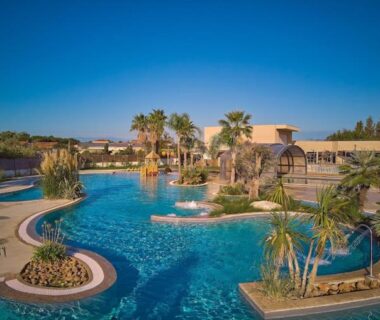 Piscine lagon avec palmiers et passerelles au Mobil Home 6 personnes du Camping les dunes 5 étoiles