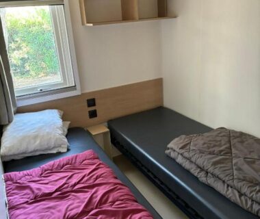 Chambre avec deux lits simples et fenêtre dans le mobil home Camping les Dunes