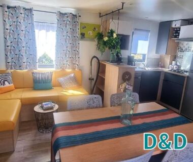 Intérieur salon avec canapé et kitchenette dans le Bungalow M027 du Camping les dunes Torreilles Plages