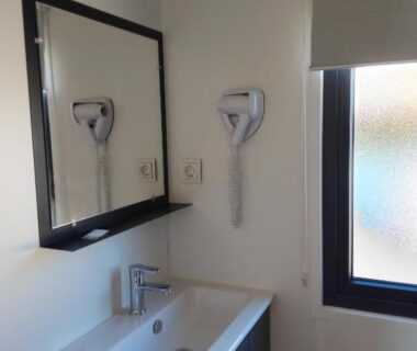 Salle de bain avec lavabo miroir et sèche cheveux dans le Camping les lodges du lagon