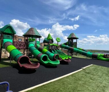 Aire de jeux extérieure avec grands toboggans verts au Camping les lodges du lagon