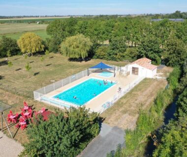 Piscine extérieure entourée de terrasse et pelouse au Camping l'île Cariot