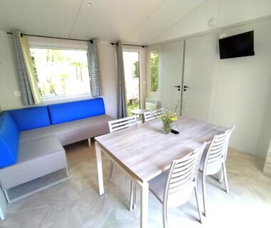 Intérieur lumineux avec table chaises et banquette dans le mobil home du Camping l'île Cariot
